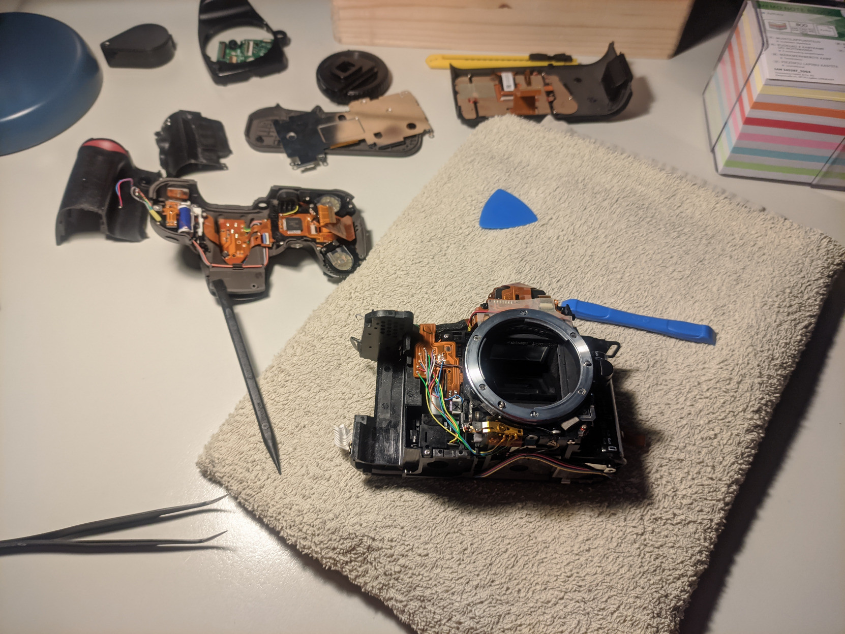 A photo showing the whole internal assembly of the camera laying on a towel, surrounded by the many pieces of the outside casing and some tools.