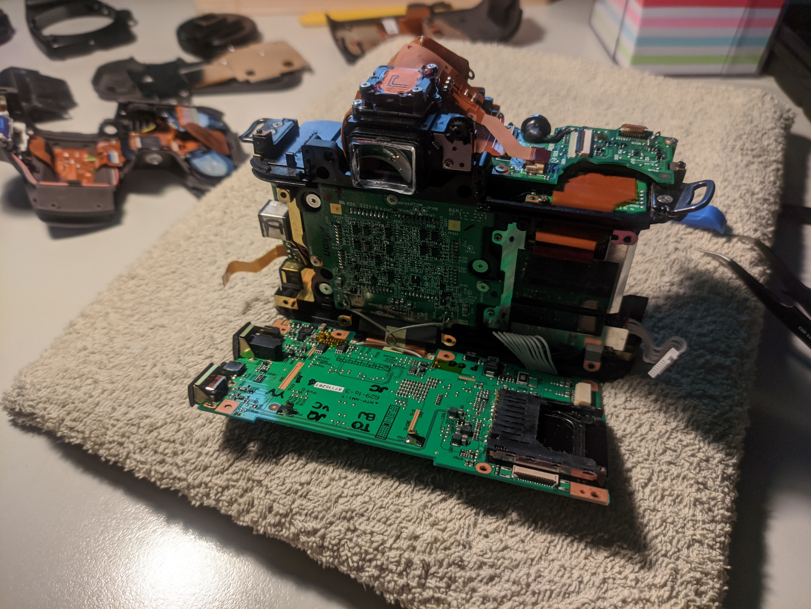 A photo of the back of the whole internal camera assembly with the outside shell and some internal components taken off. There are multiple green PCBs, one hanging on a few ribbon cables. One of them houses the sensor of the camera.