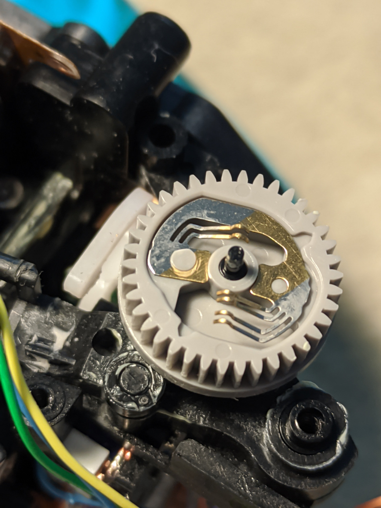 A close up of the plastic gear. You can very clearly see that on the left there is a plastic cap holding the metal contacts in place, while on the right it's missing.